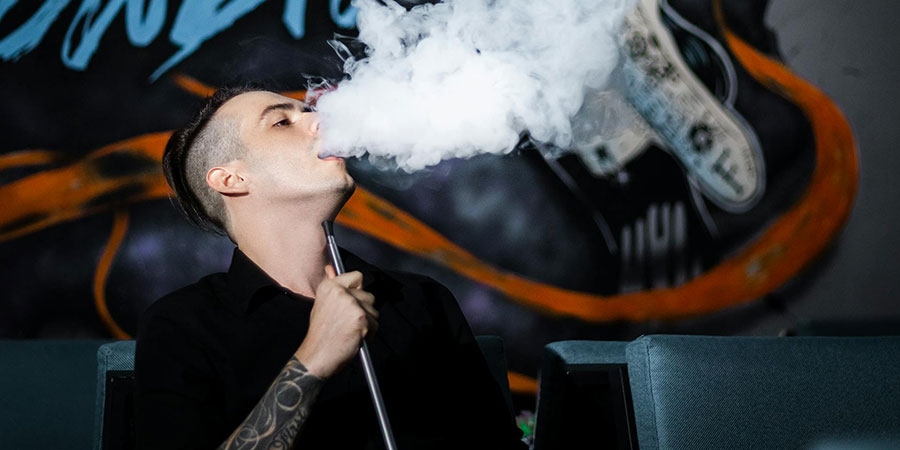 a man with tattoo on his arm smoking vape